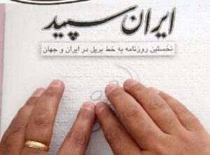 دست فرد نابینا روی روزنامه ایران سپید قرار گرفته