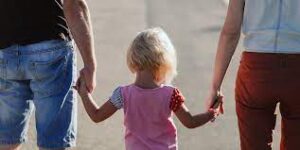 پدر و مادری دست کودک خود را گرفته و راه میروند (عکس از پشت سر گرفته شده)