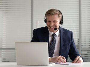 آقای نابینا در مکالمه تصویری با استفاده از لپتاپ به سمت لپتاپ نگاه میکند و لبخند میزند.