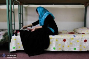 خانمی در حال اتوی لباس روی تخت خوابگاه