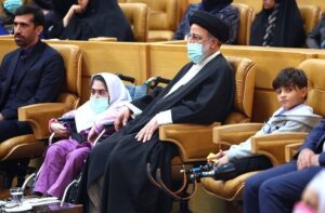 آقای رئیسی در سالن همایش، بین دو کودک با معلولیت پا نشسته
