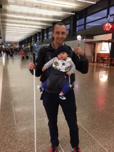 پدر نابینا با نوزادی در آغوش با عصای سفید راه می رود