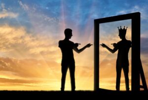 شخصی که بدون تاجی بر سر جلوی آینه ایستاده و در خیالاتش خود را در آینه با تاجی بر سر میبیند