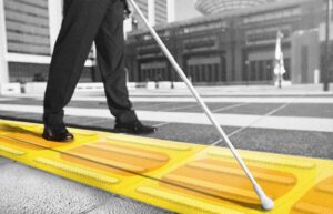 راه رفتن فردی با عصای سفید روی کاشی زرد پیاده رو