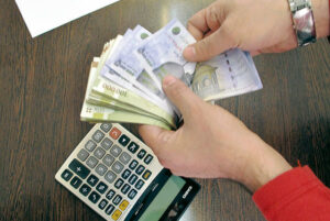 فردی در حال شمارس اسکناس - ماشین حساب روی میز 
